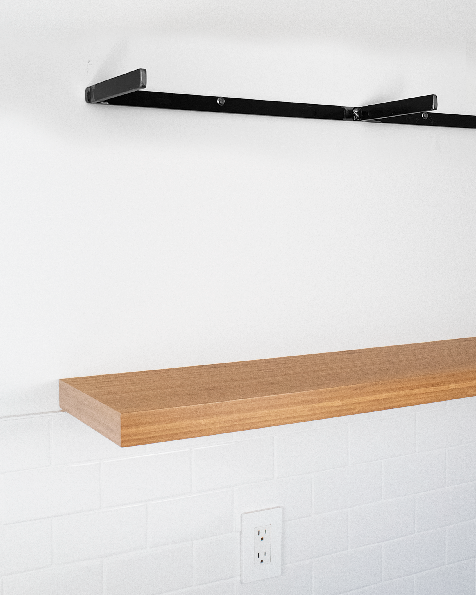 a metal floating shelf bracket mounted on a wall above a bamboo floating shelf below