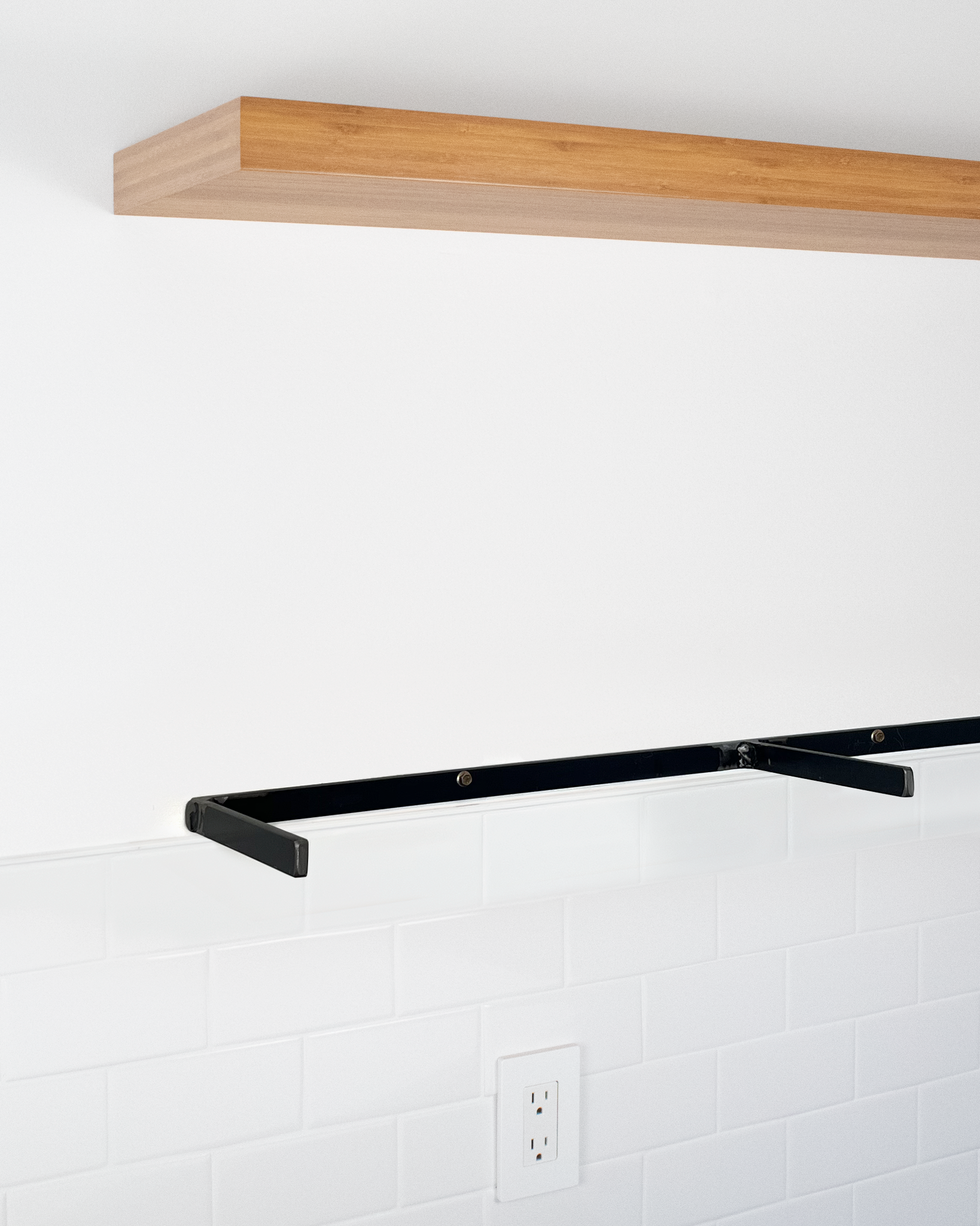 side angle view of a bamboo floating shelf mounted on a wall with a metal floating shelf bracket mounted below