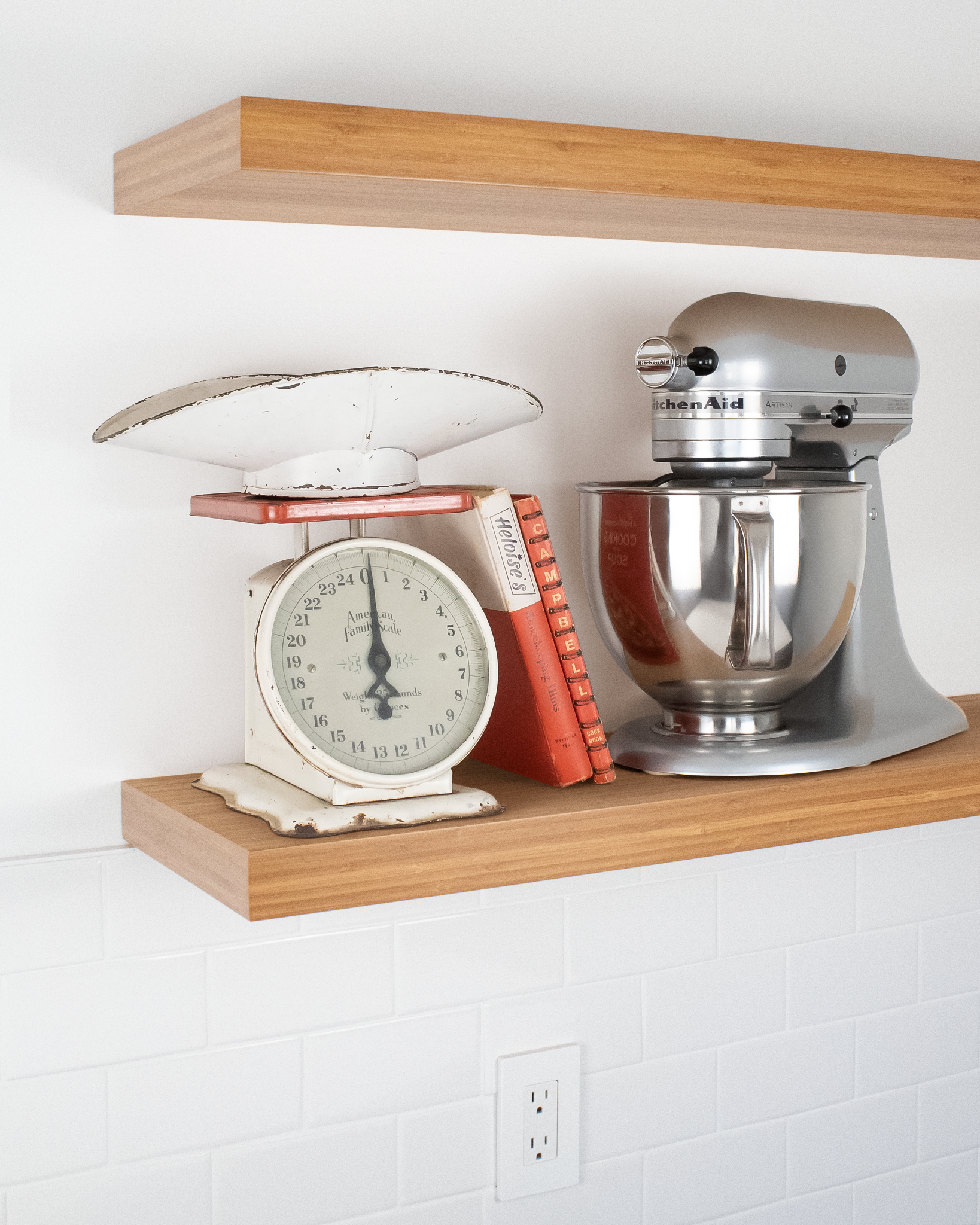 side angle view of two bamboo floating shelves on a wall with the bottom shelf holding a mixer and scale