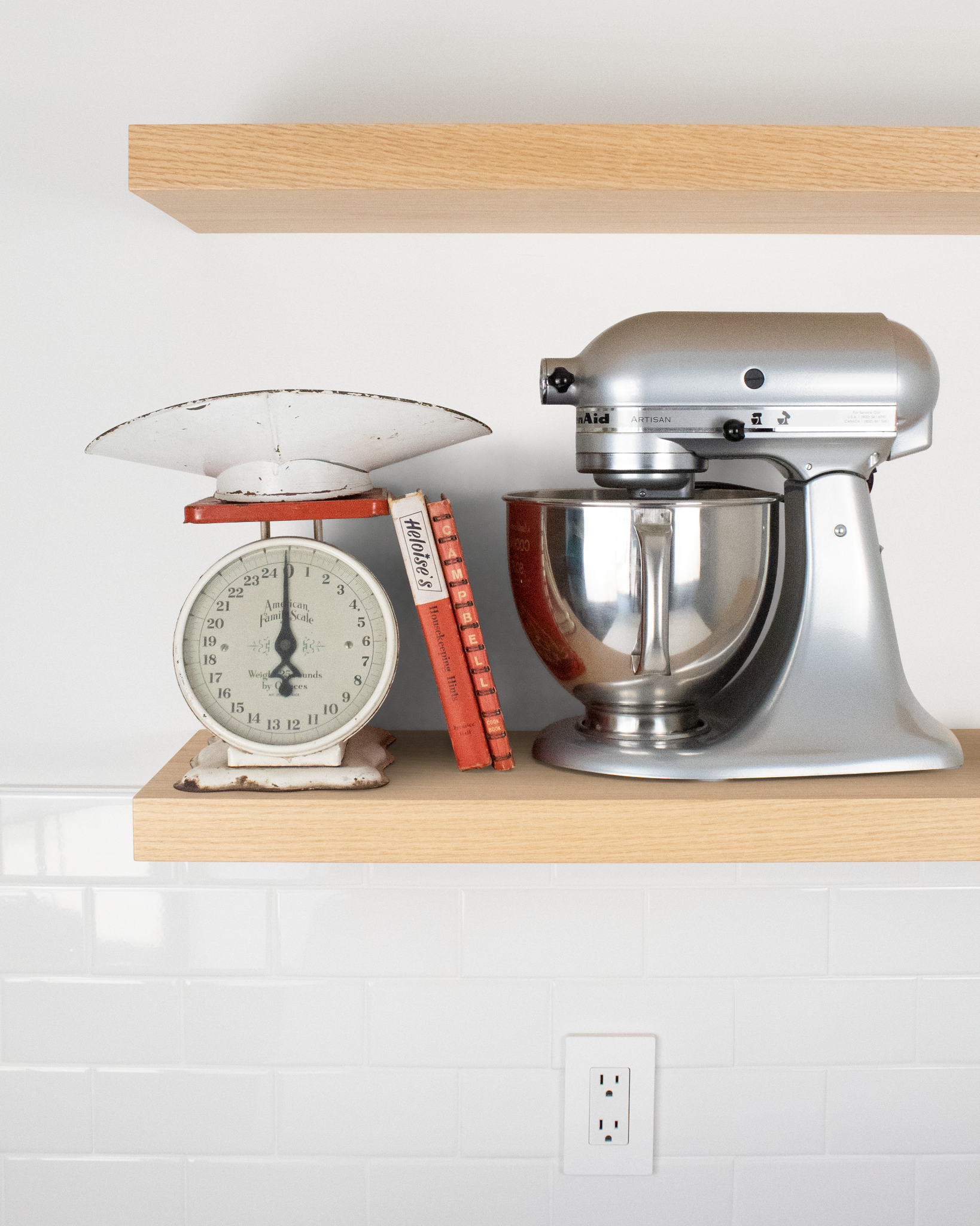 Two light oak floating shelves mounted on a wall with accessories on the bottom shelf