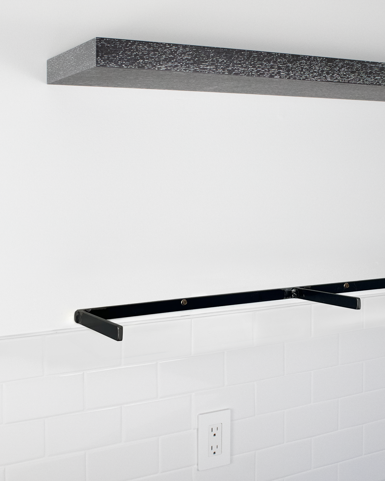Dark oak floating shelf above metal bracket mounted on wall