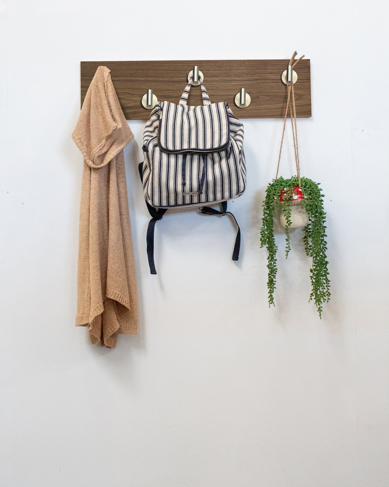 Walnut Wood wall hook rack satin nickel hooks with a backpack, coat, and plant