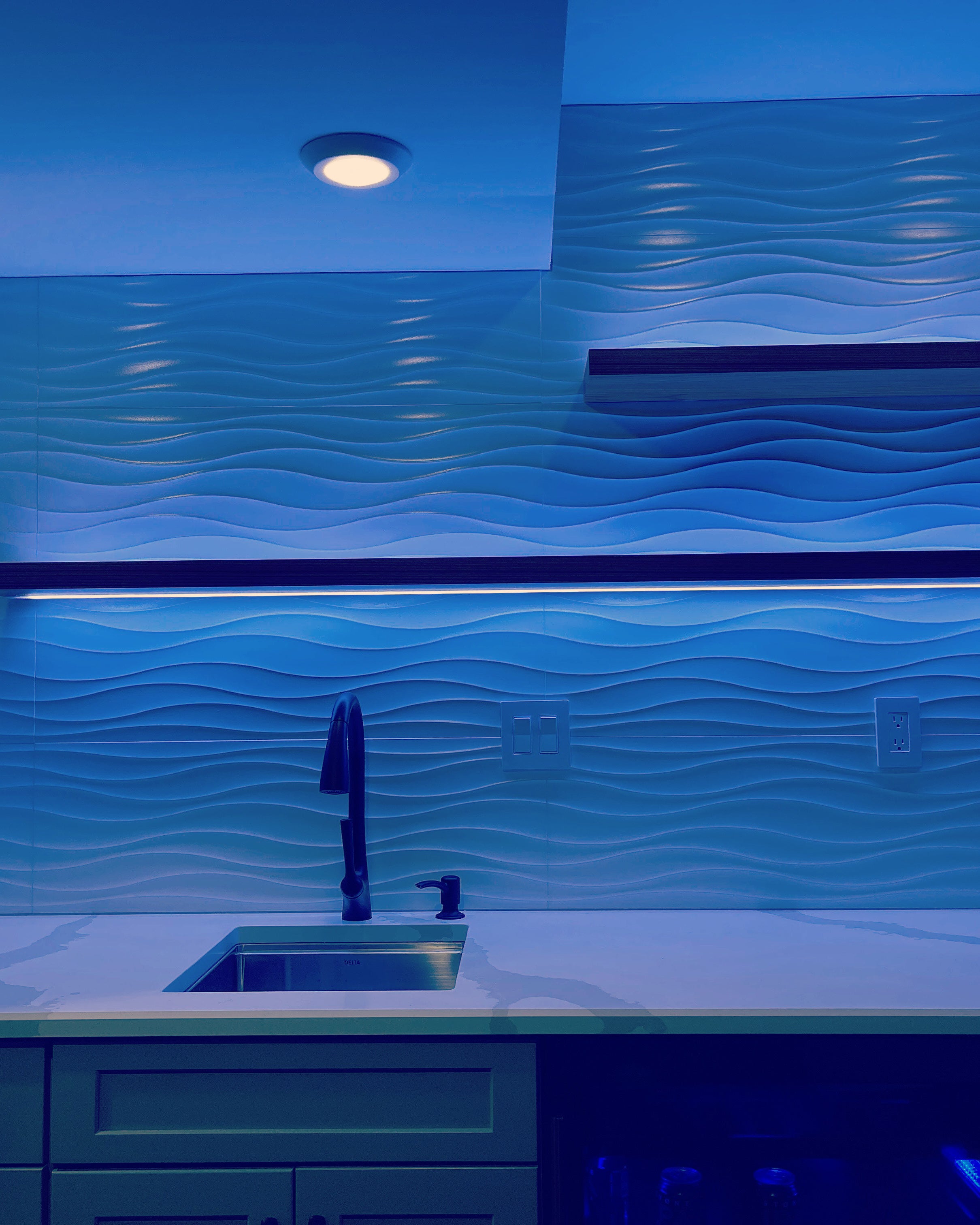 Floating shelves in a wet bar area with lighting channels to illuminate wall
