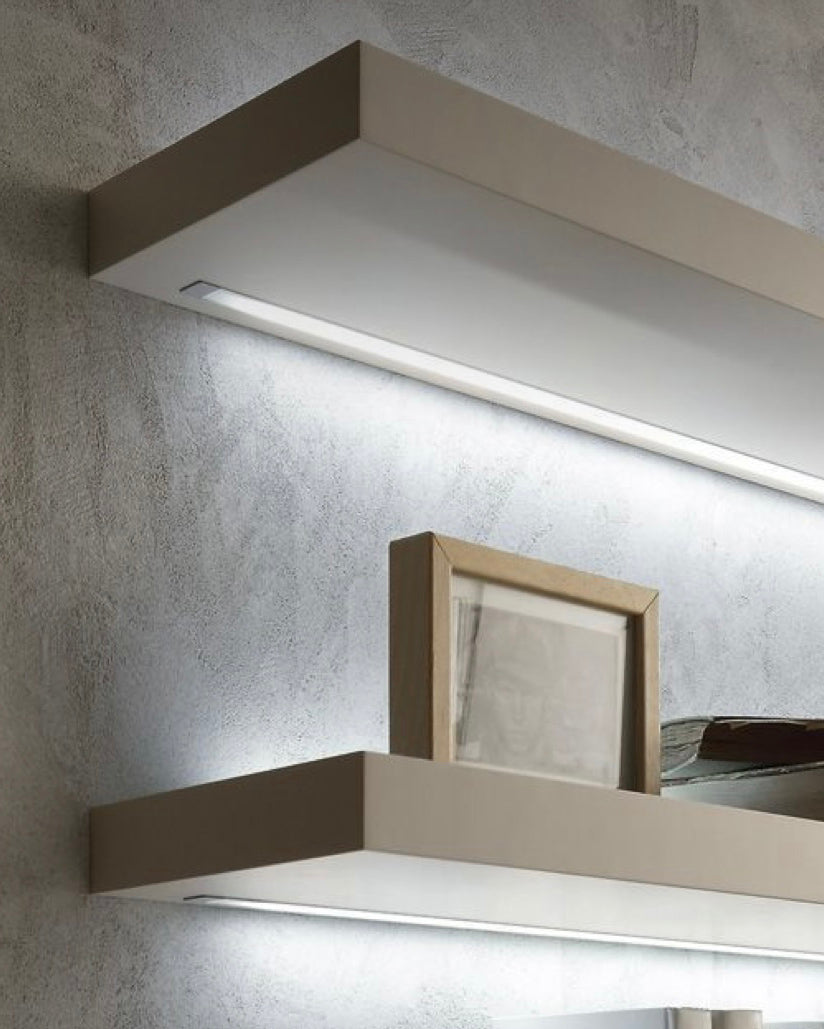White shelves with lighting channels underneath illuminating accessories on wall