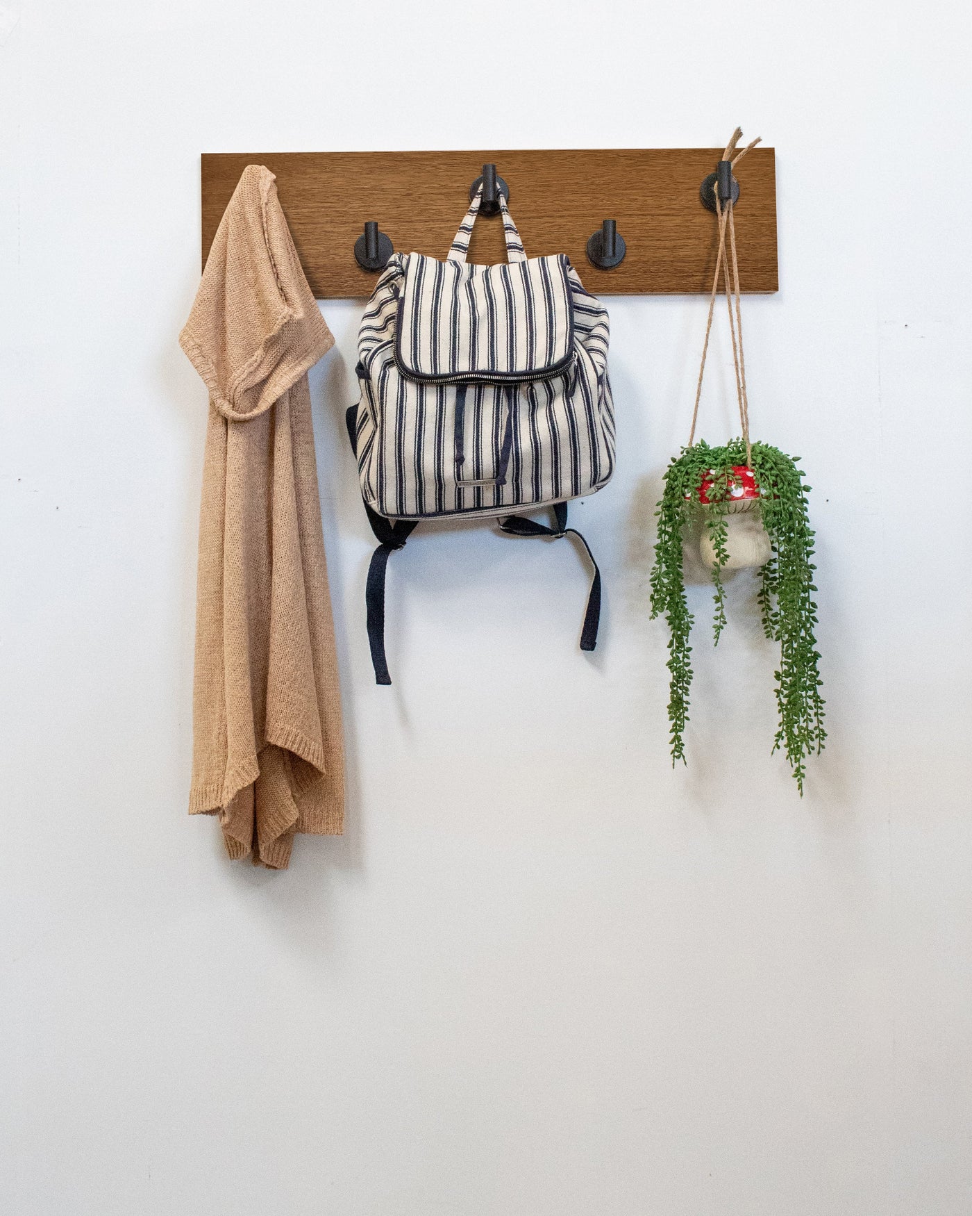 African mahogany Wood wall hook rack matte black hooks with a backpack, coat, and plant