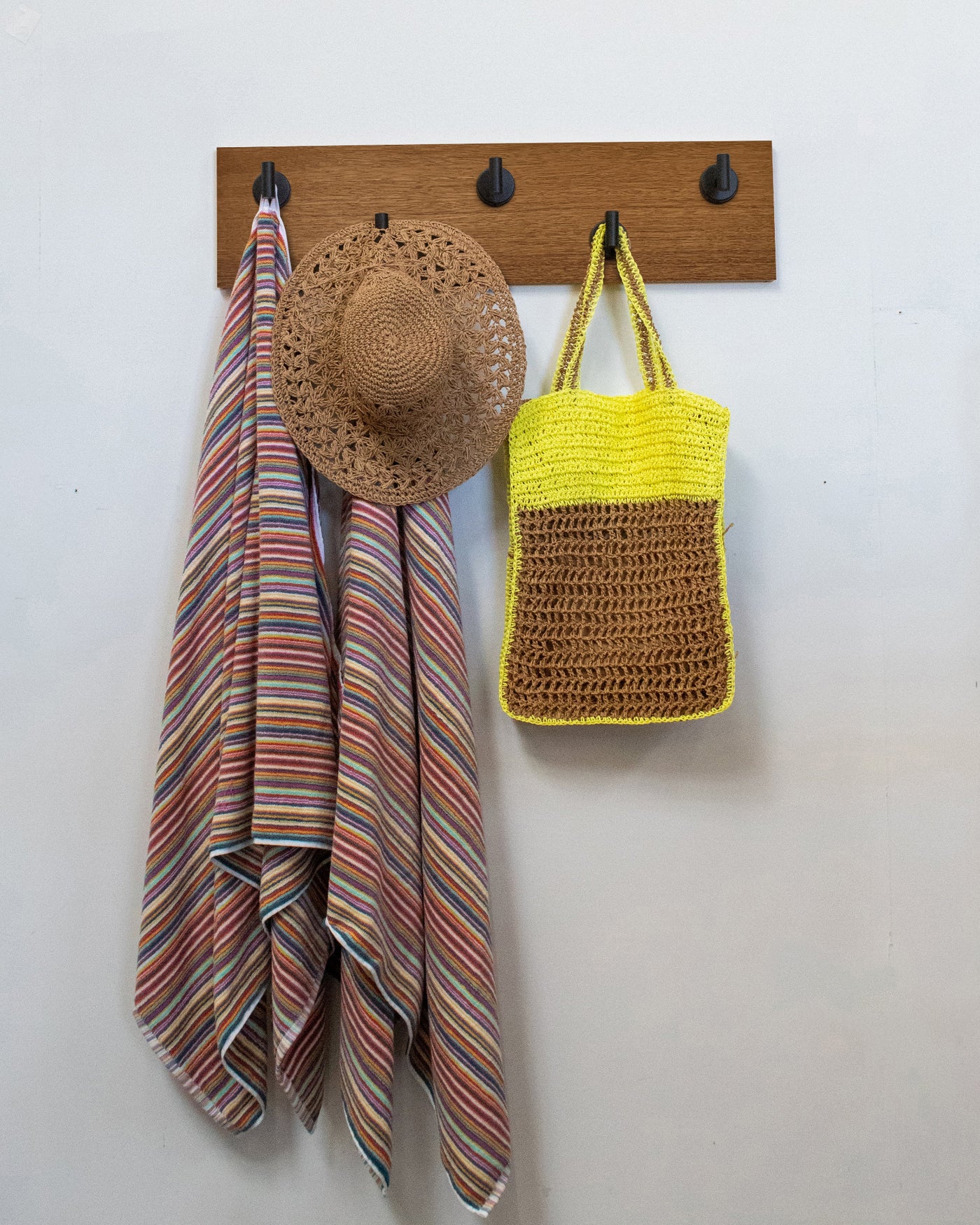 African mahogany wood wall hook rack with 5 matte black hooks, striped towel, straw hat, and yellow bag