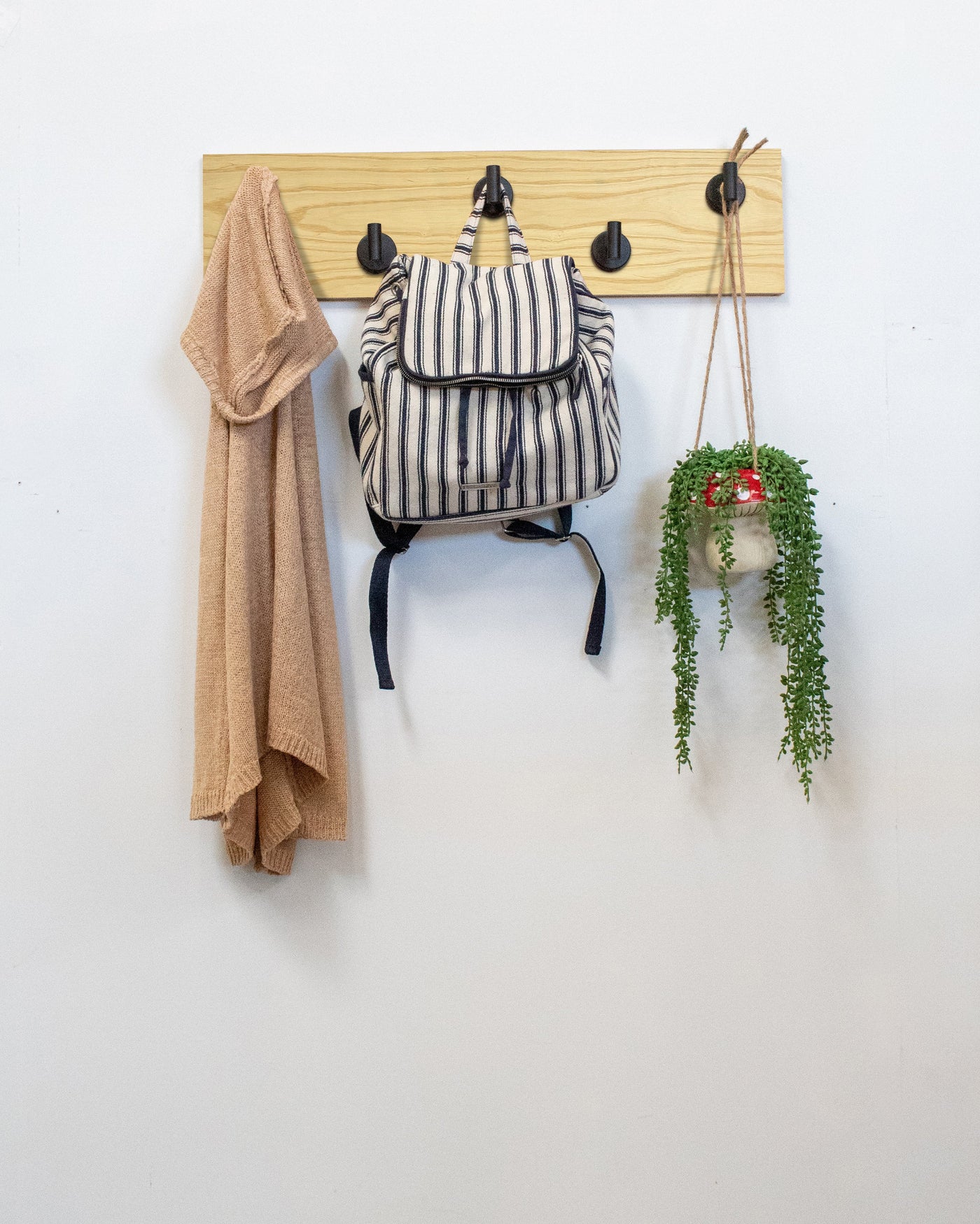 Ash Wood wall hook rack matte black hooks with a backpack, coat, and plant