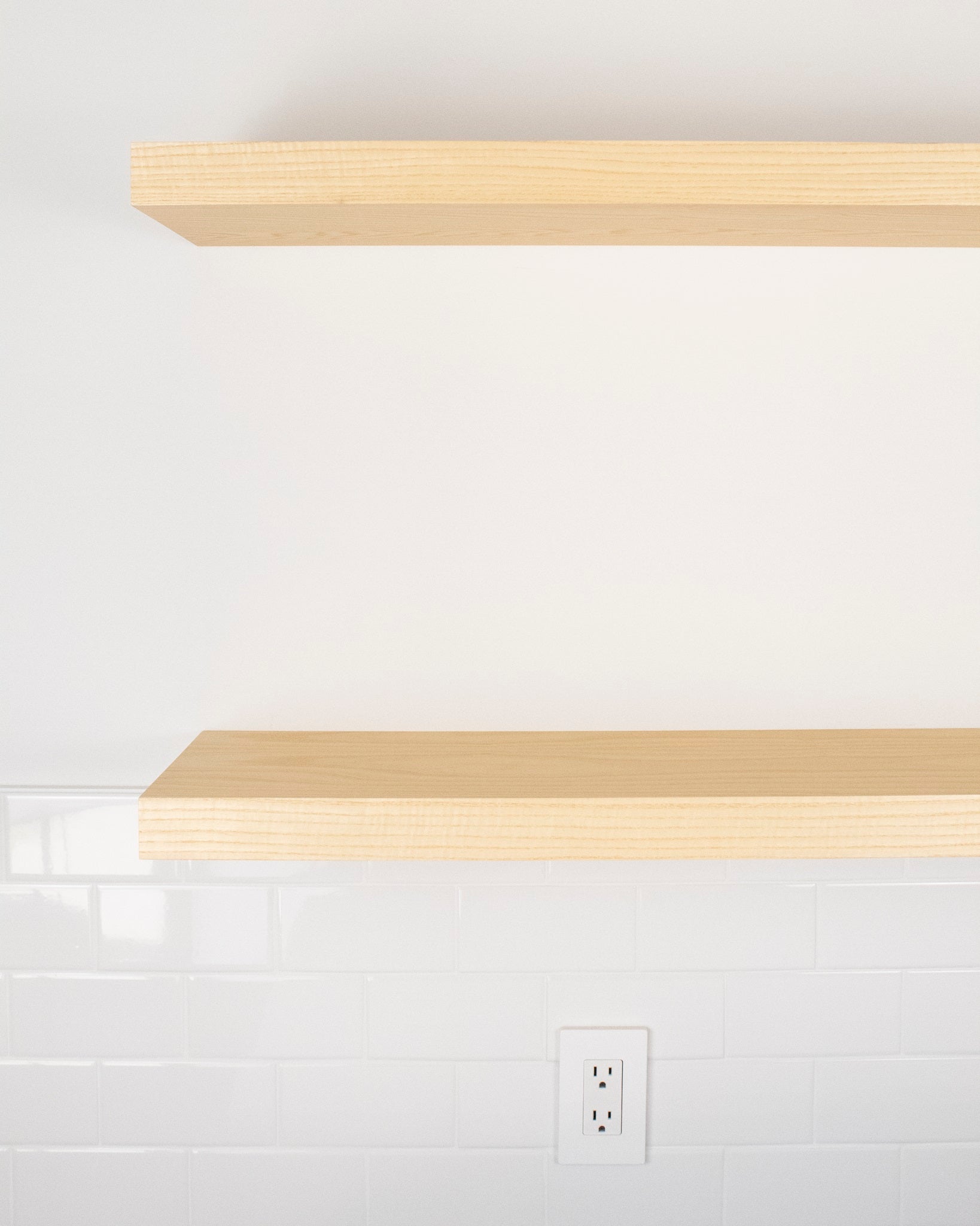 Two ash wood floating shelves mounted to a wall