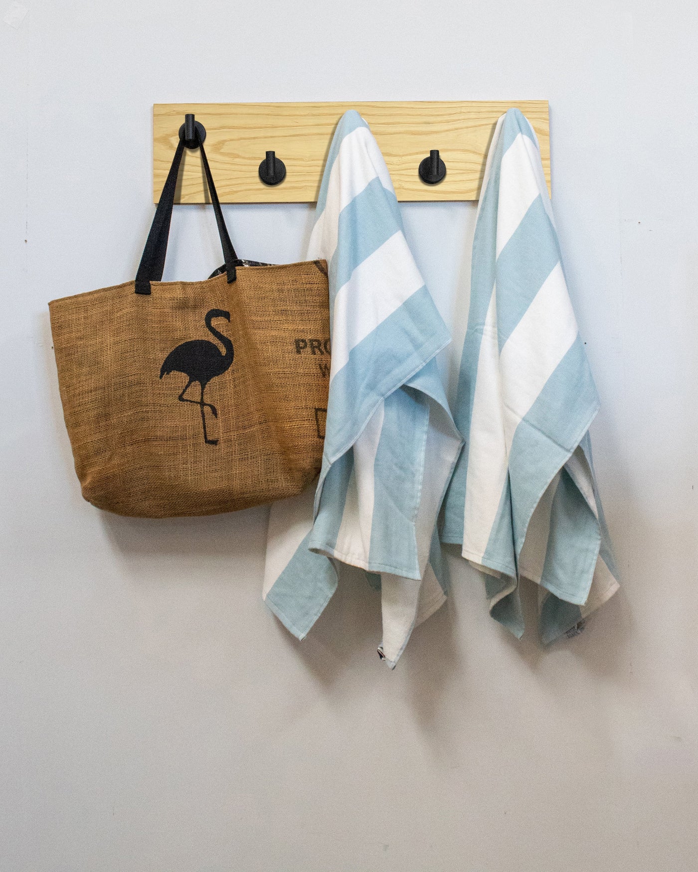Ash wood wall hook rack brown tote bag with flamingo design and two striped towels hanging on 5 matte black hooks 