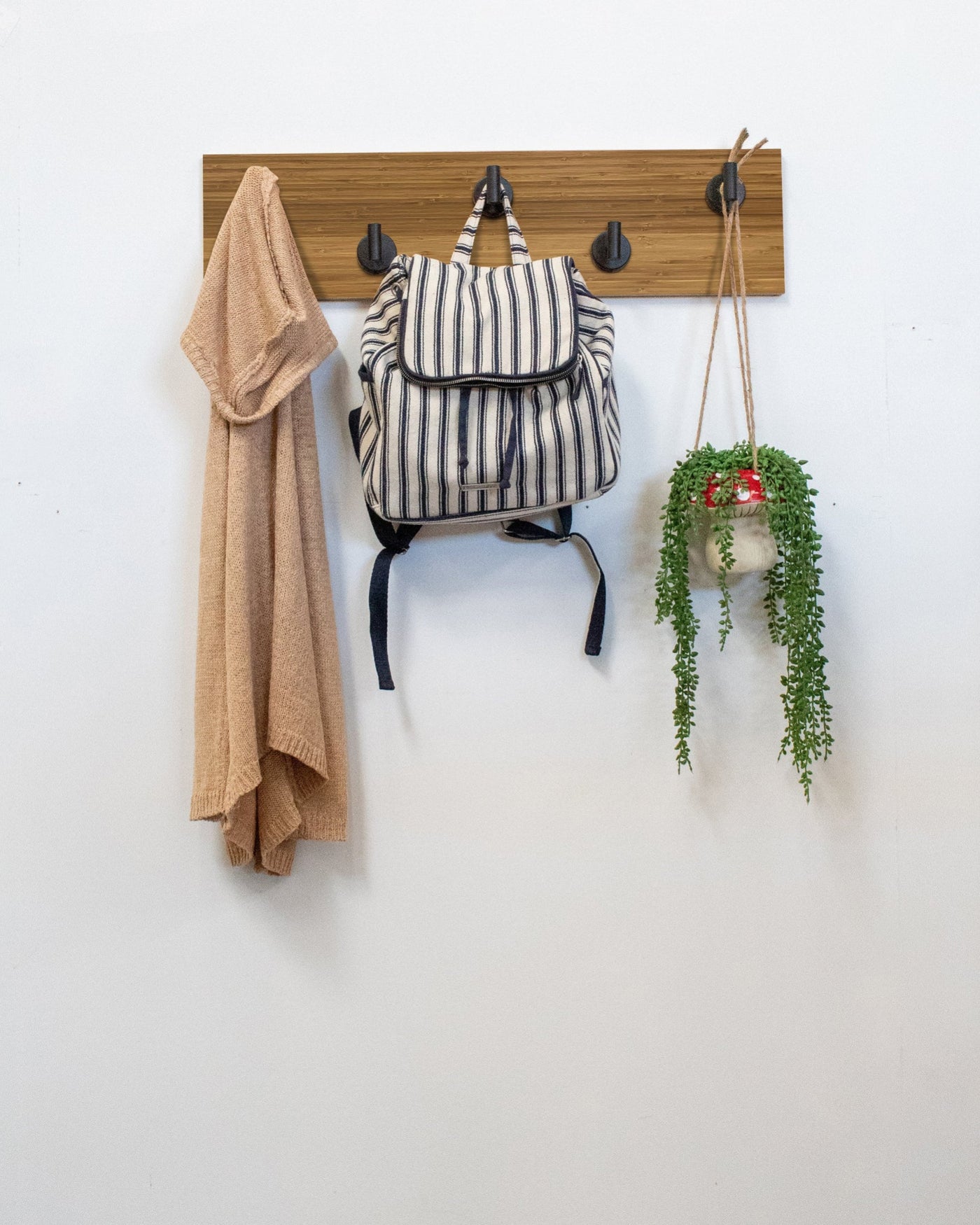 Bamboo Wood wall hook rack matte black hooks with a backpack, coat, and plant