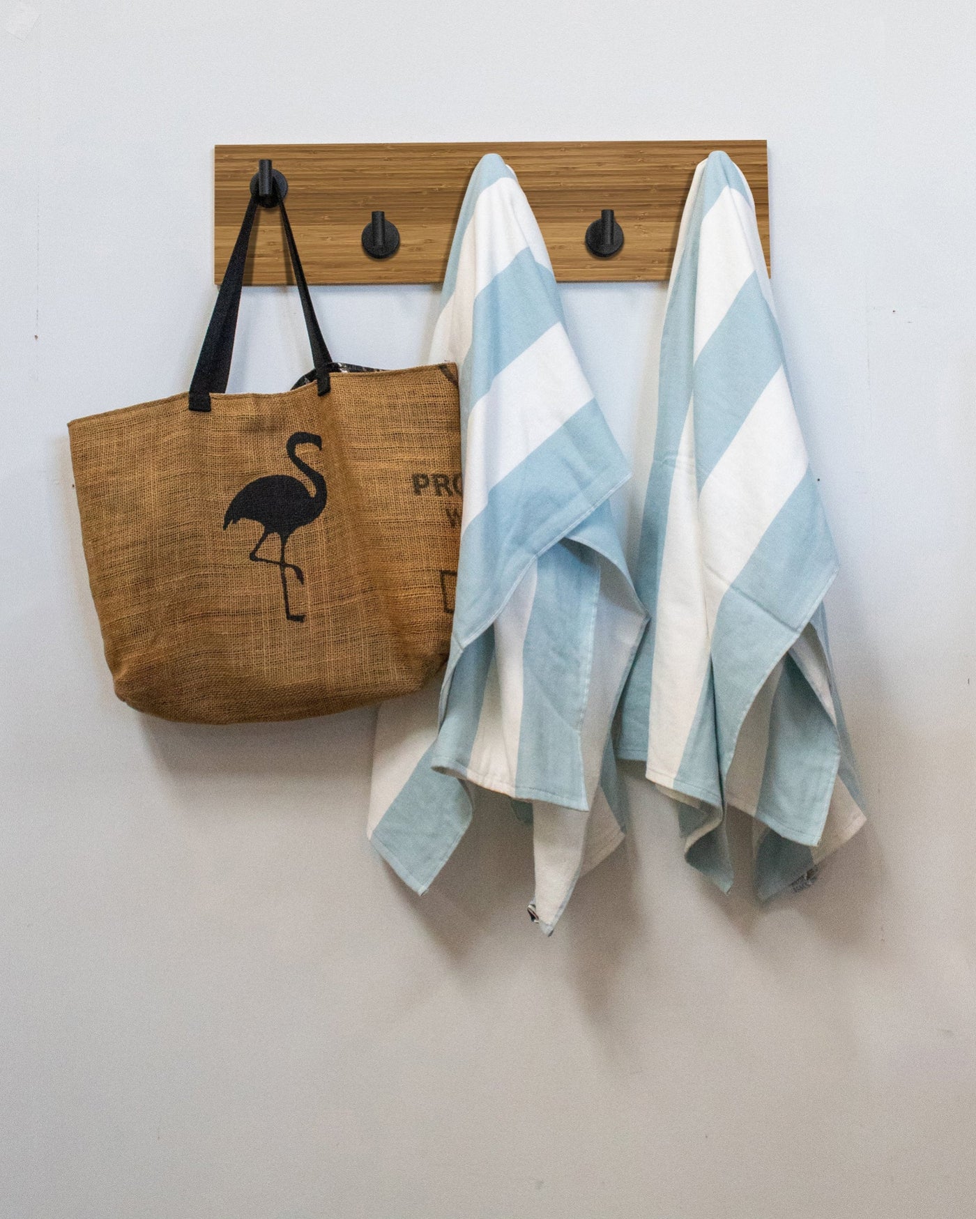 Bamboo wood wall hook rack brown tote bag with flamingo design and two striped towels hanging on 5 matte black hooks 