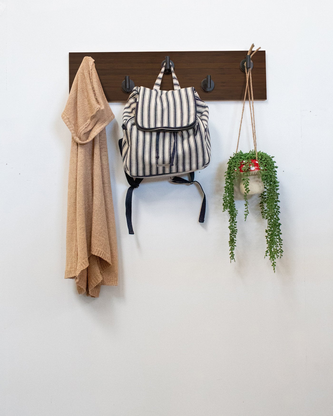 Chocolate Bamboo Wood wall hook rack matte black hooks with a backpack, coat, and plant