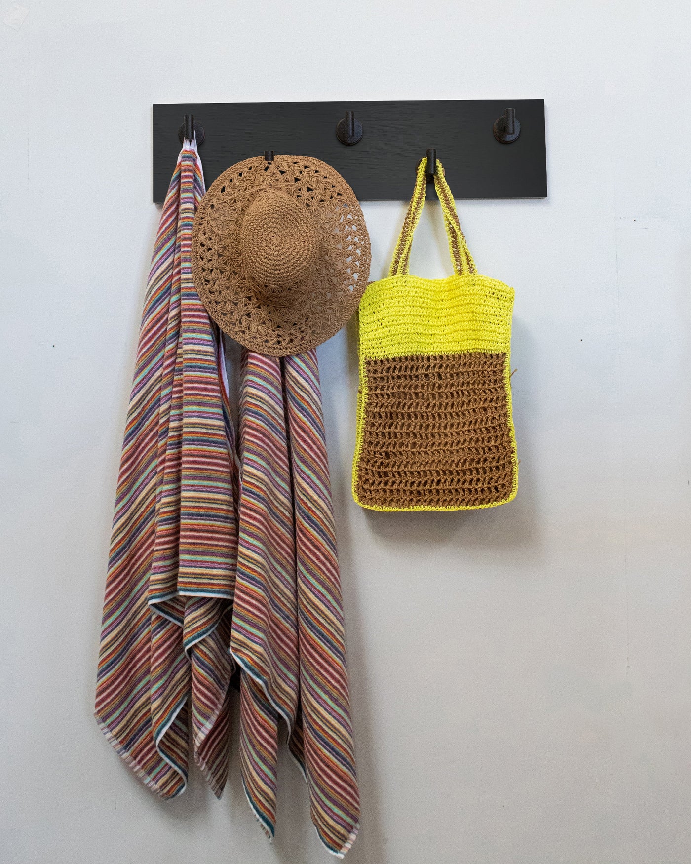 Chocolate espresso oak wall hook rack with 5 matte black hooks, striped towel, straw hat, and yellow bag