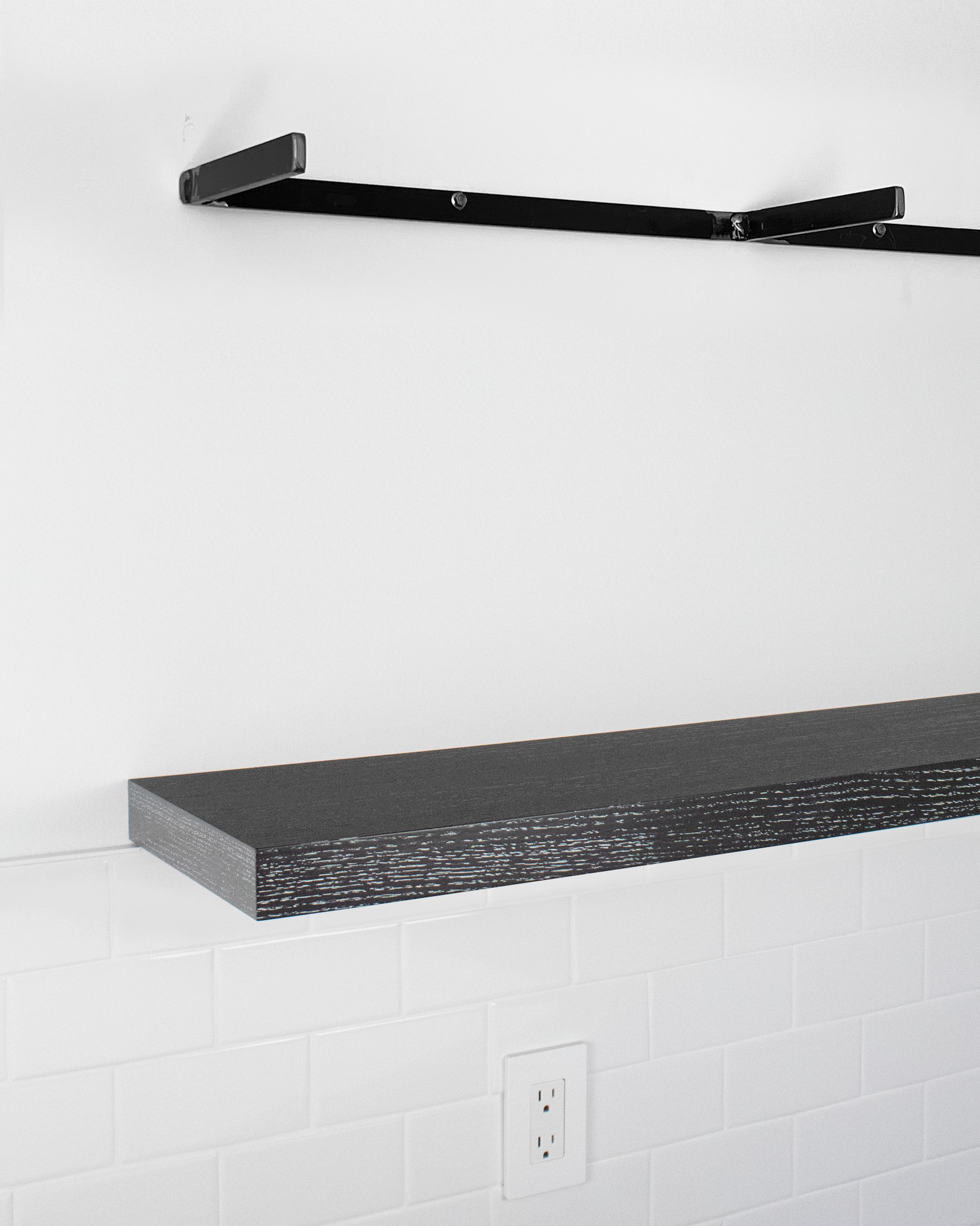 Metal floating shelf bracket above dark oat floating shelf on wall