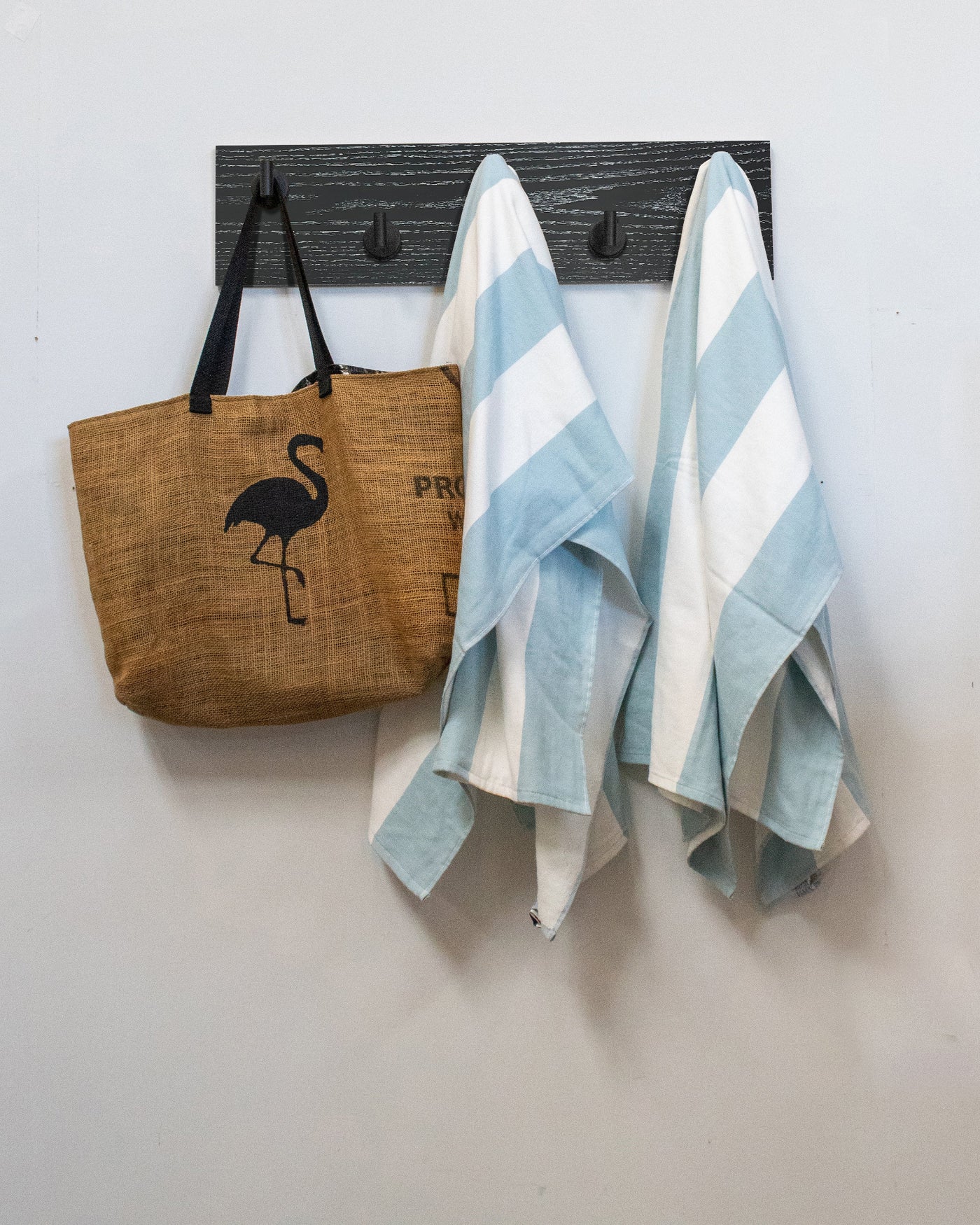 Ebonized cerused oak wall hook rack brown tote bag with flamingo design and two striped towels hanging on 5 matte black hooks 