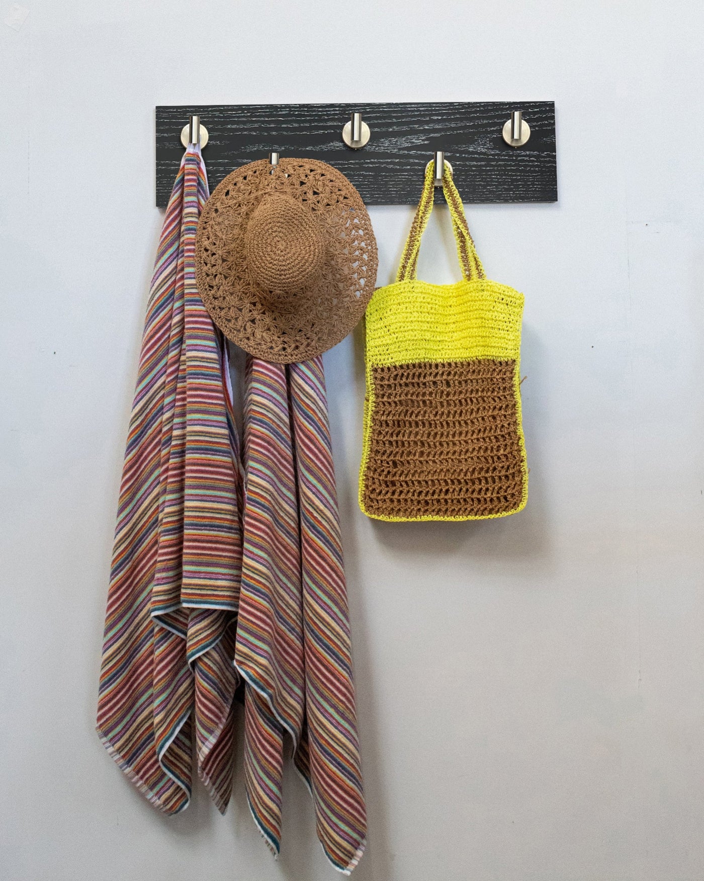 Ebonized cerused oak wall hook rack with 5 satin nickel hooks, striped towel, straw hat, and yellow bag