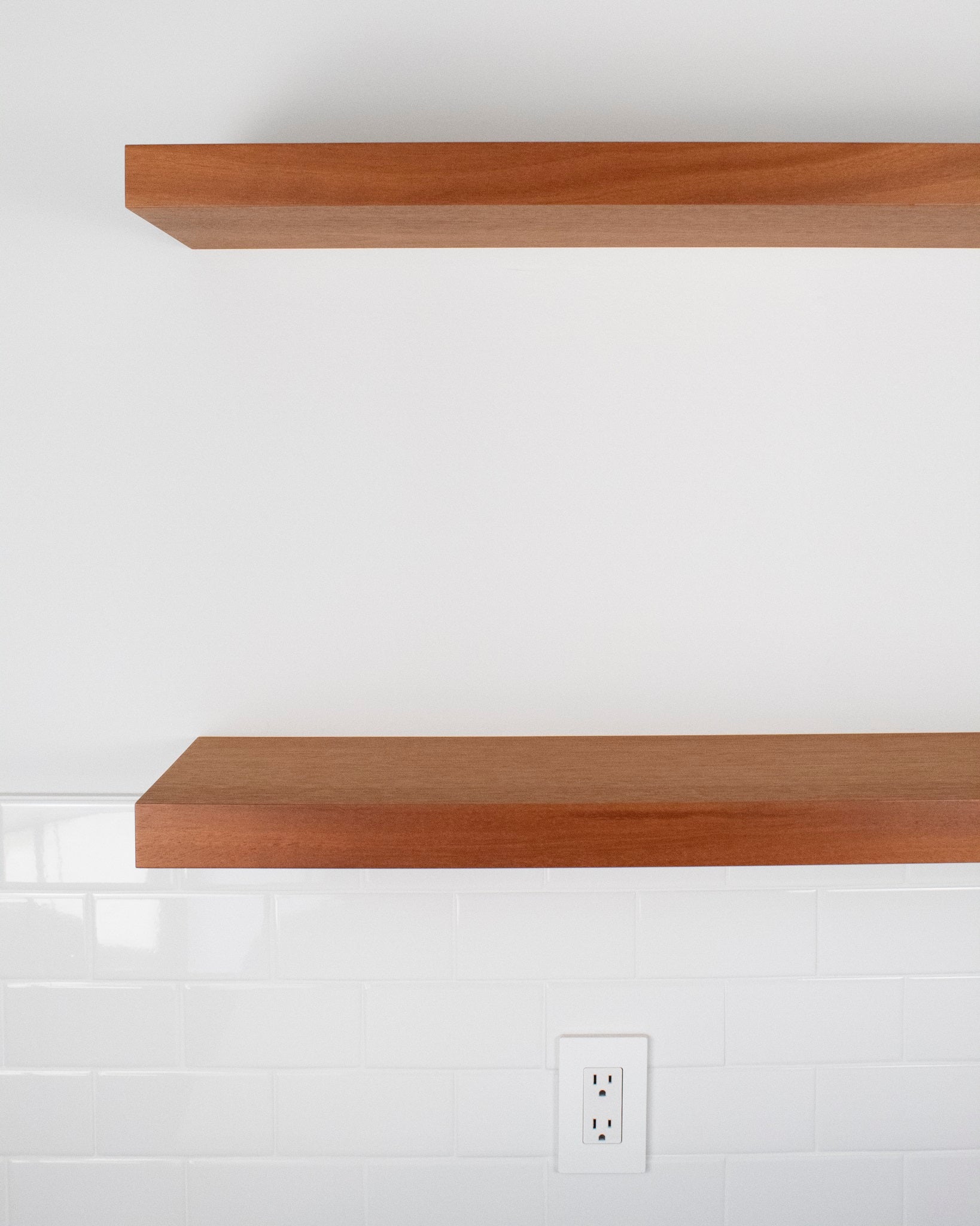 two wood floating shelves in african mahogany on a wall