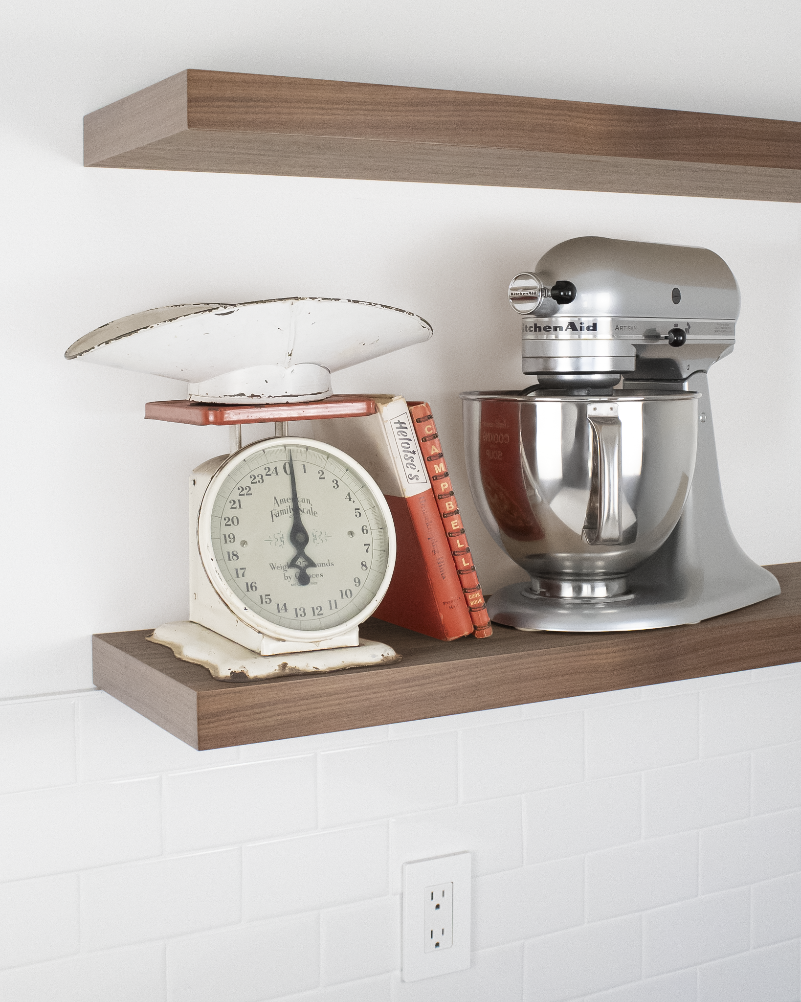 Front angle view of two walnut floating shelves displaying a mixer and food scale