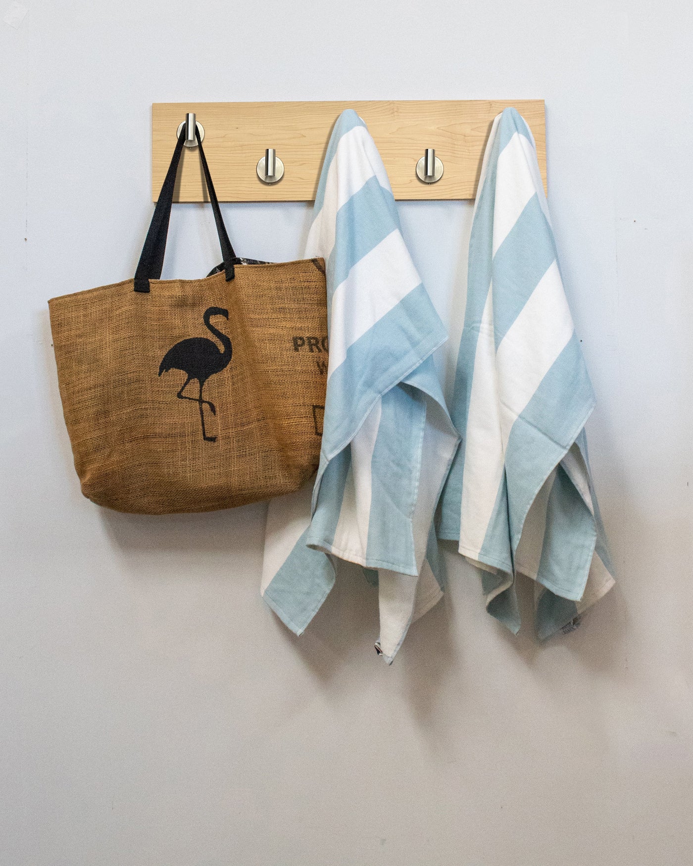 Maple wood wall hook rack with brown tote bag with flamingo design and two striped towels hanging on satin nickel hooks.