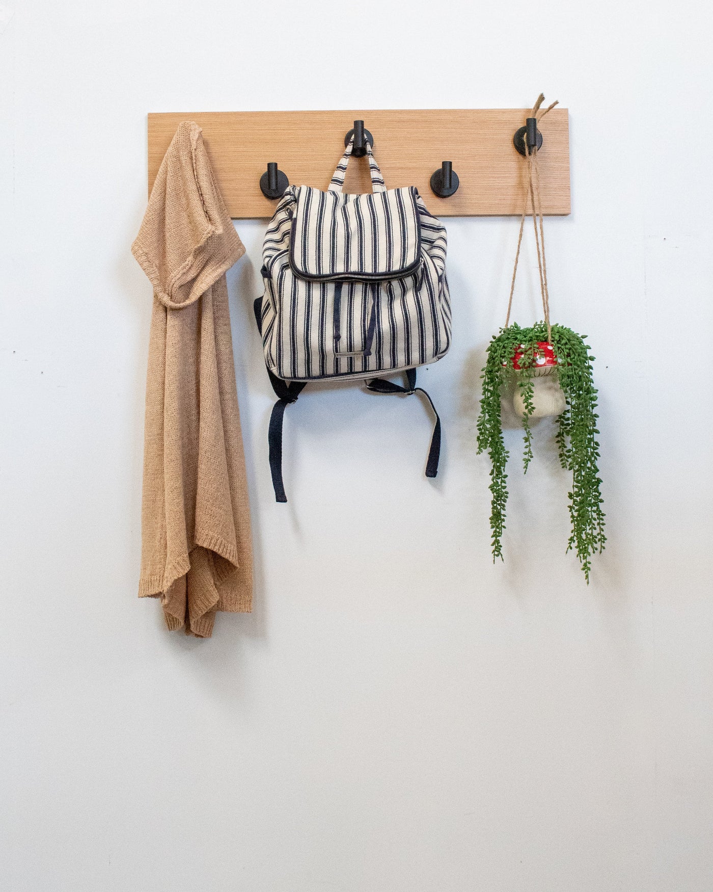 Rift white oak Wood wall hook rack matte black hooks with a backpack, coat, and plant