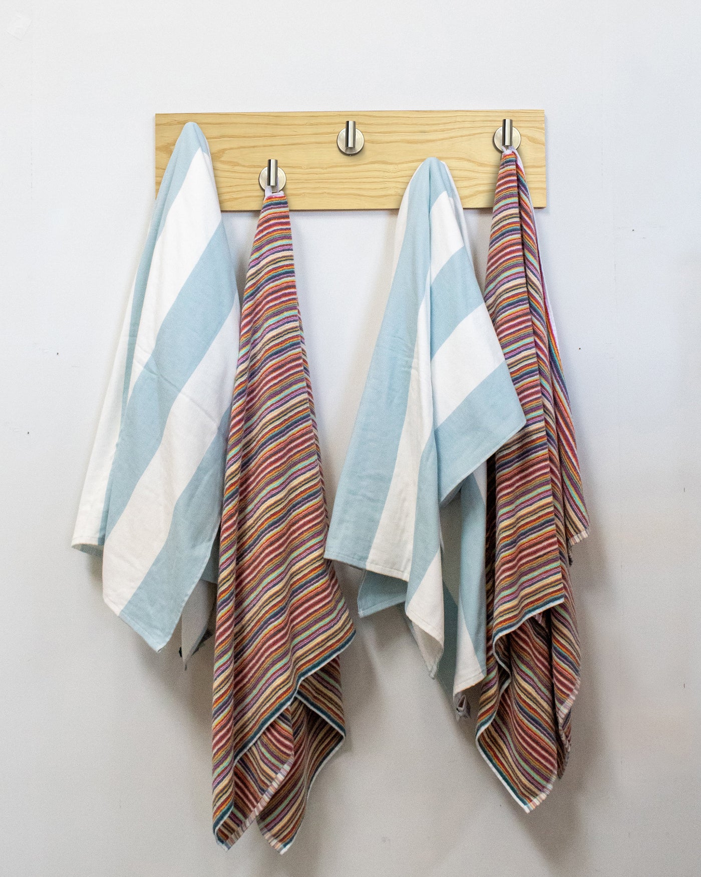 Striped towels hanging on Ash wood wall hook rack with satin nickel hooks.