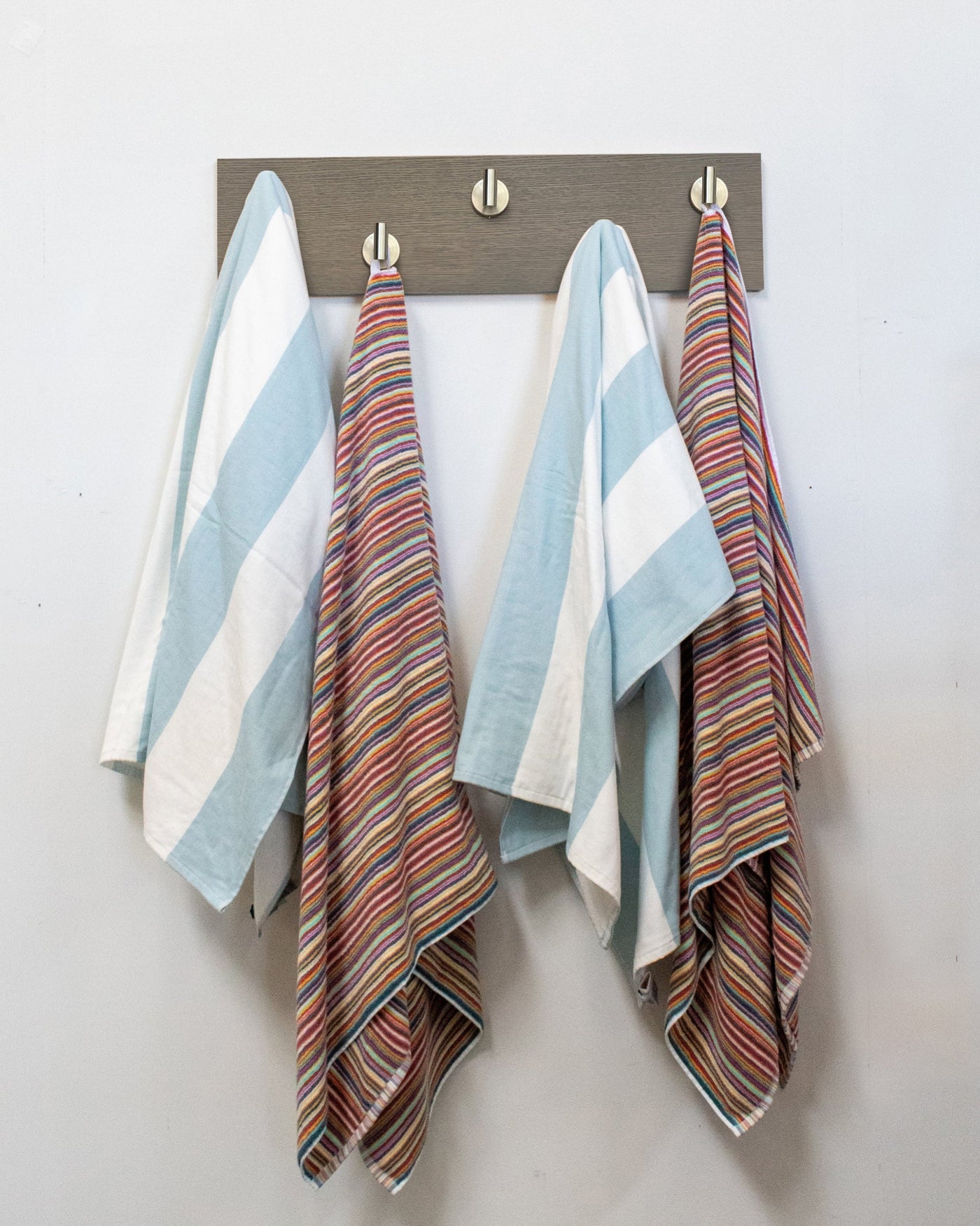 Striped towels hanging on a Driftwood Grey Oak wall hook rack with 5 satin nickel hooks