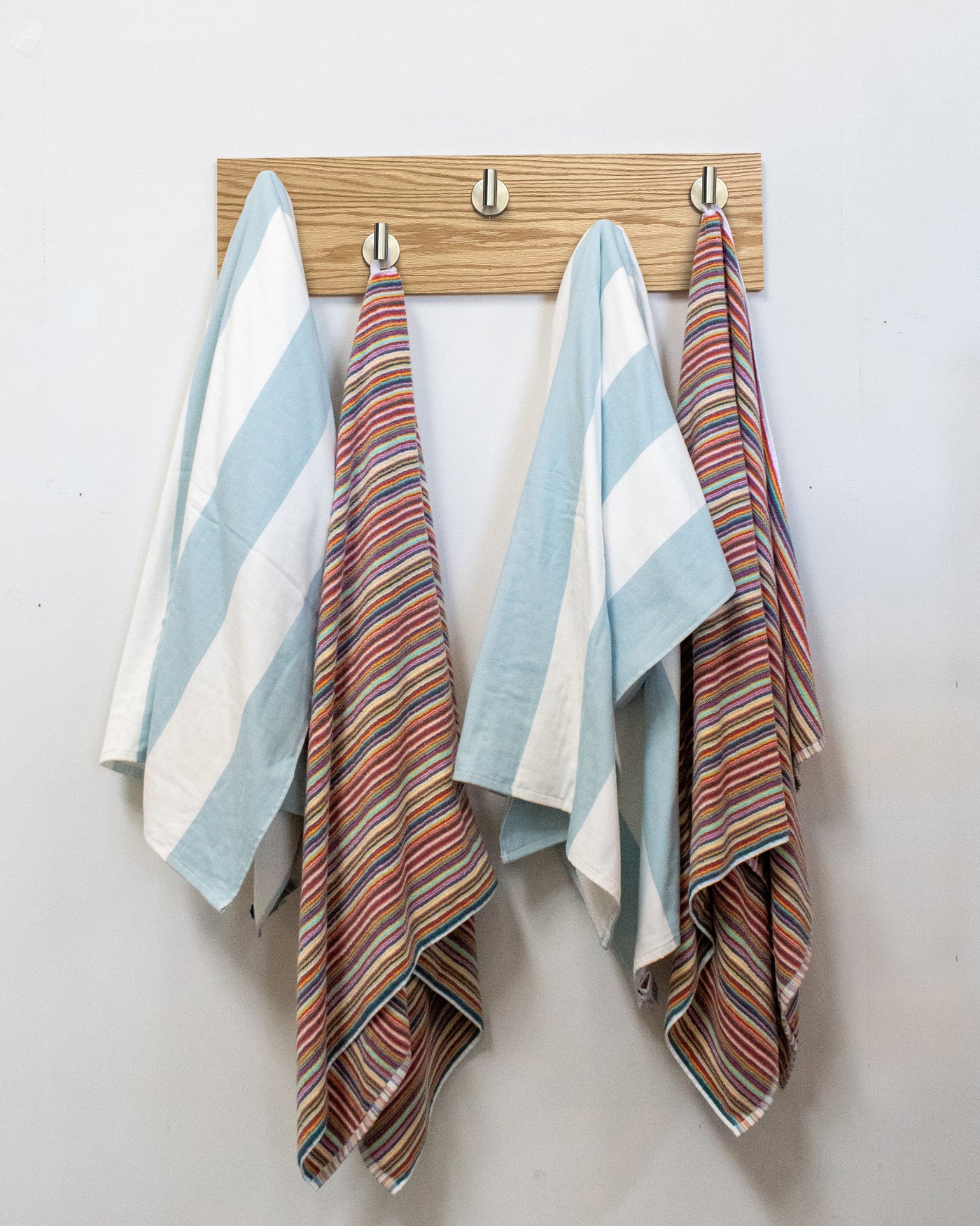 Striped towels hanging on a Red Oak wood wall hook rack with 5 satin nickelhooks
