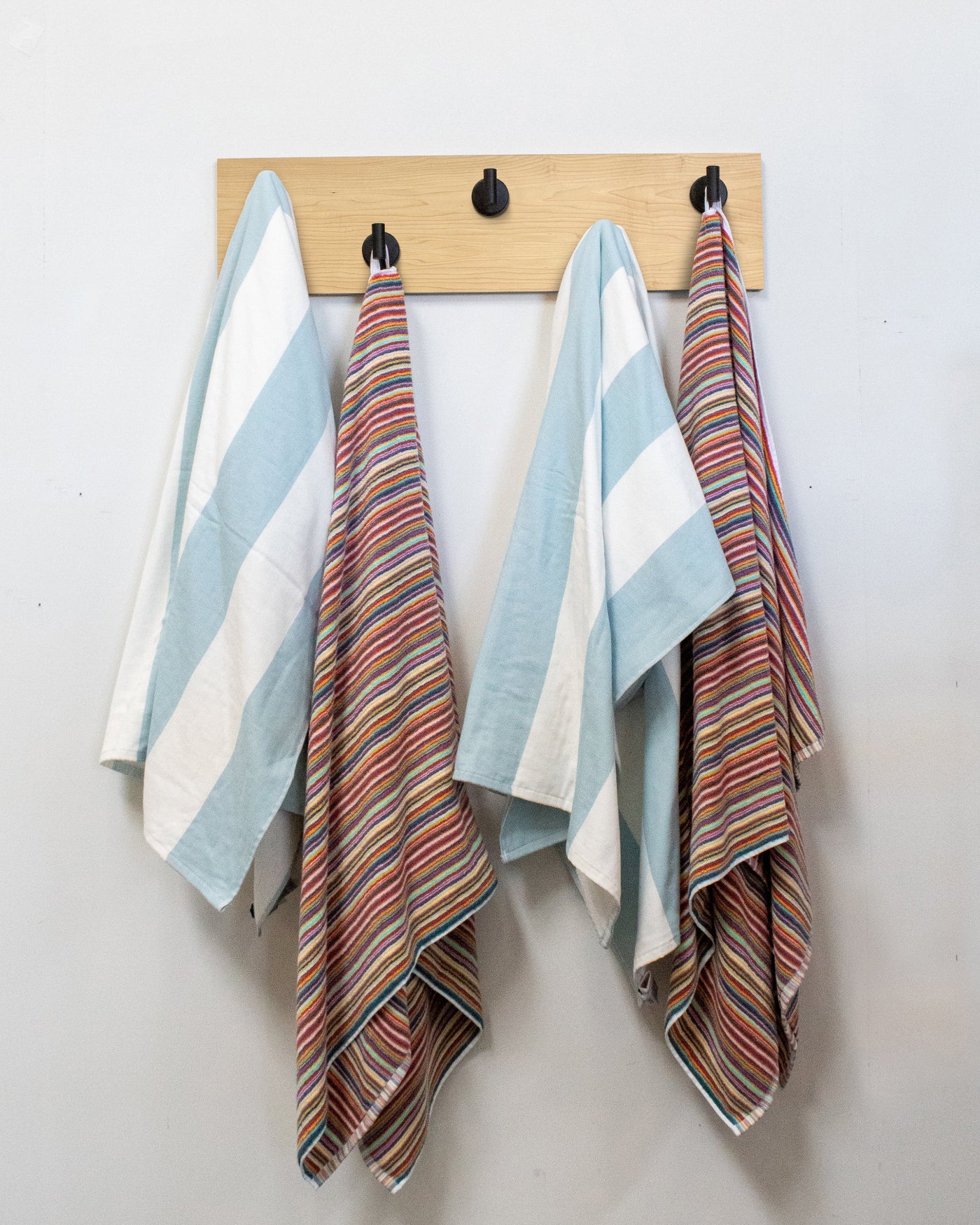 Striped towels hanging on a maple wood wall hook rack matte black hooks