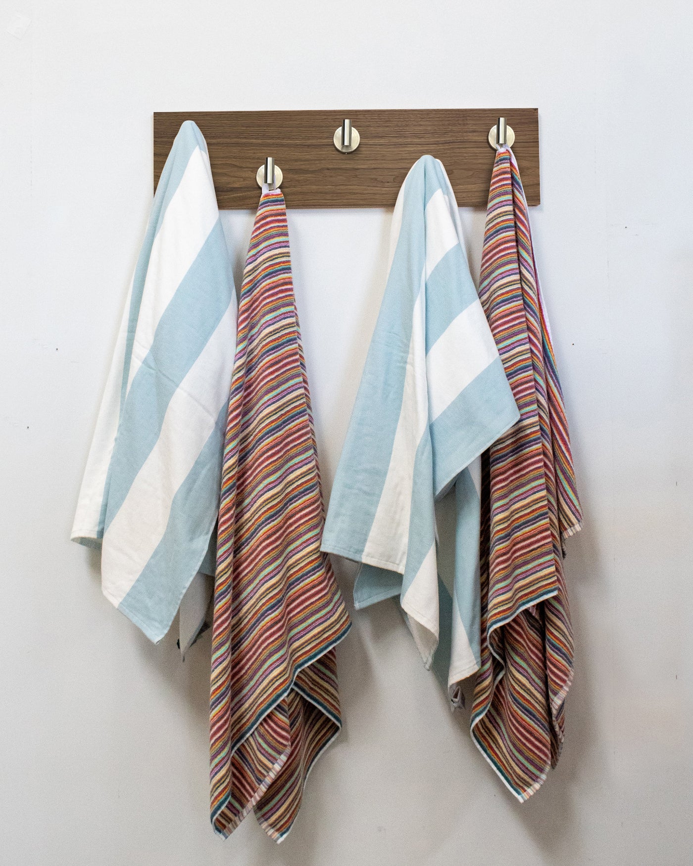 Striped towels hanging on a walnut wood wall hook rack satin nickel hooks