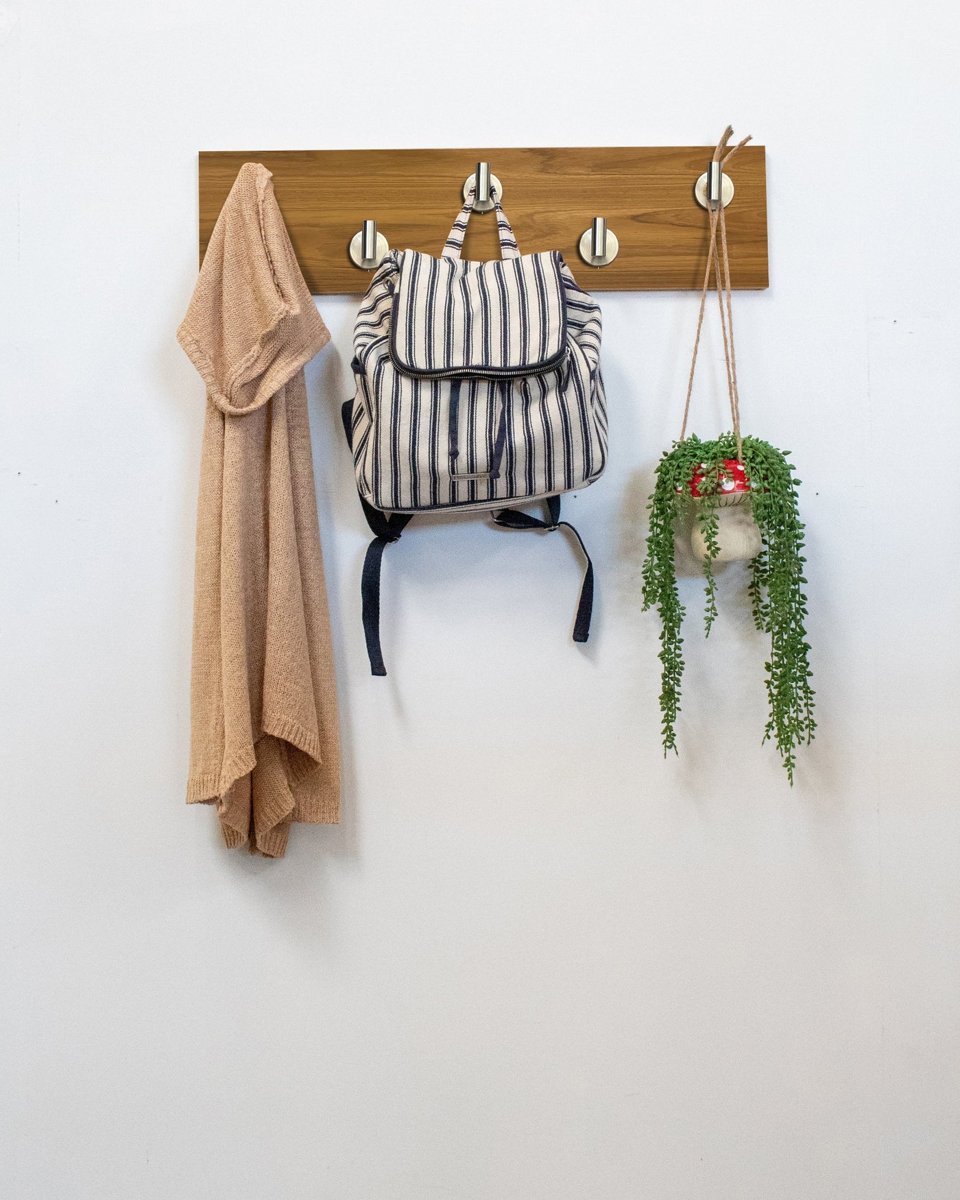 Teak Wood wall hook rack satin nickel hooks with a backpack, coat, and plant