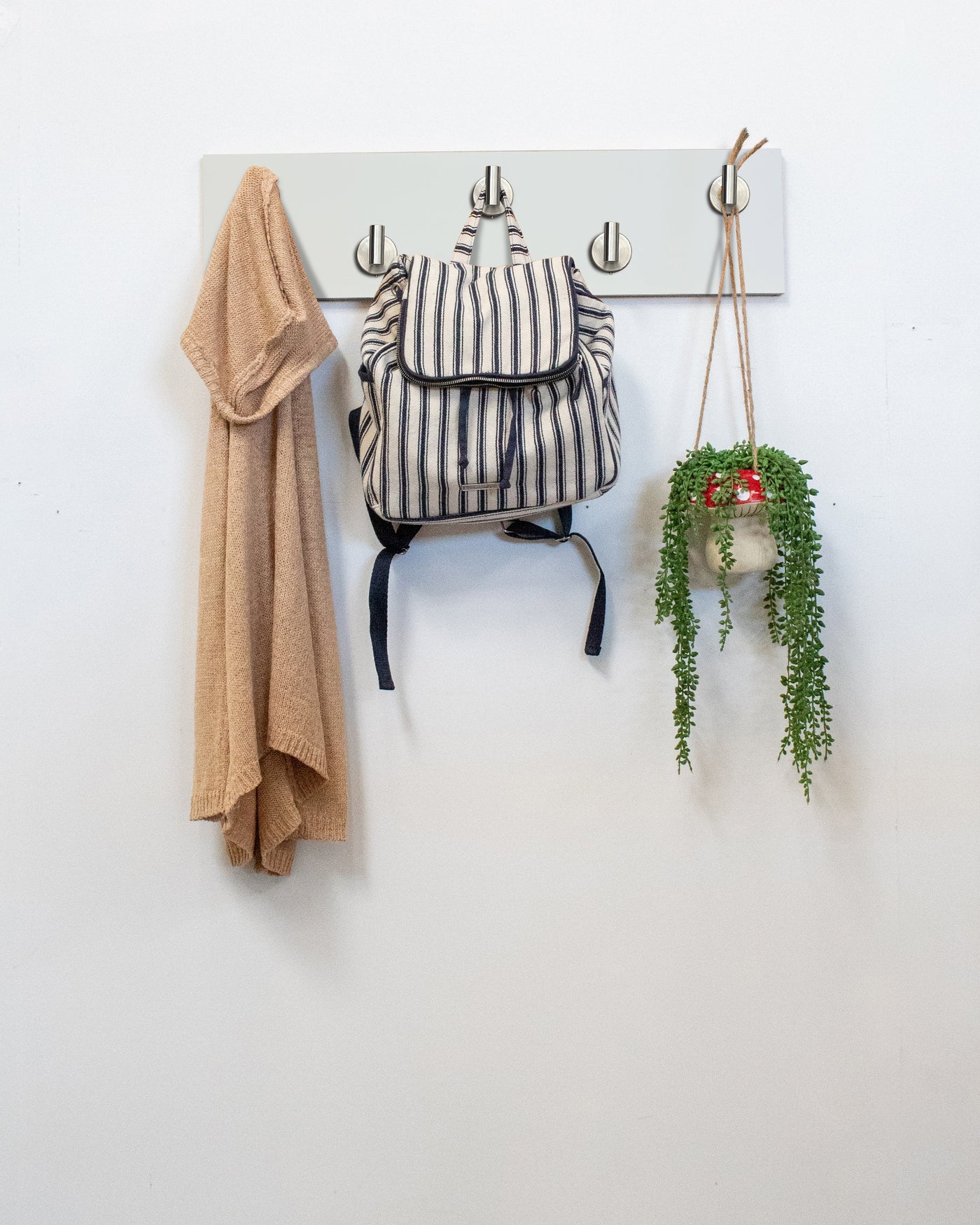 White Wood wall hook rack satin nickel hooks with a backpack, coat, and plant