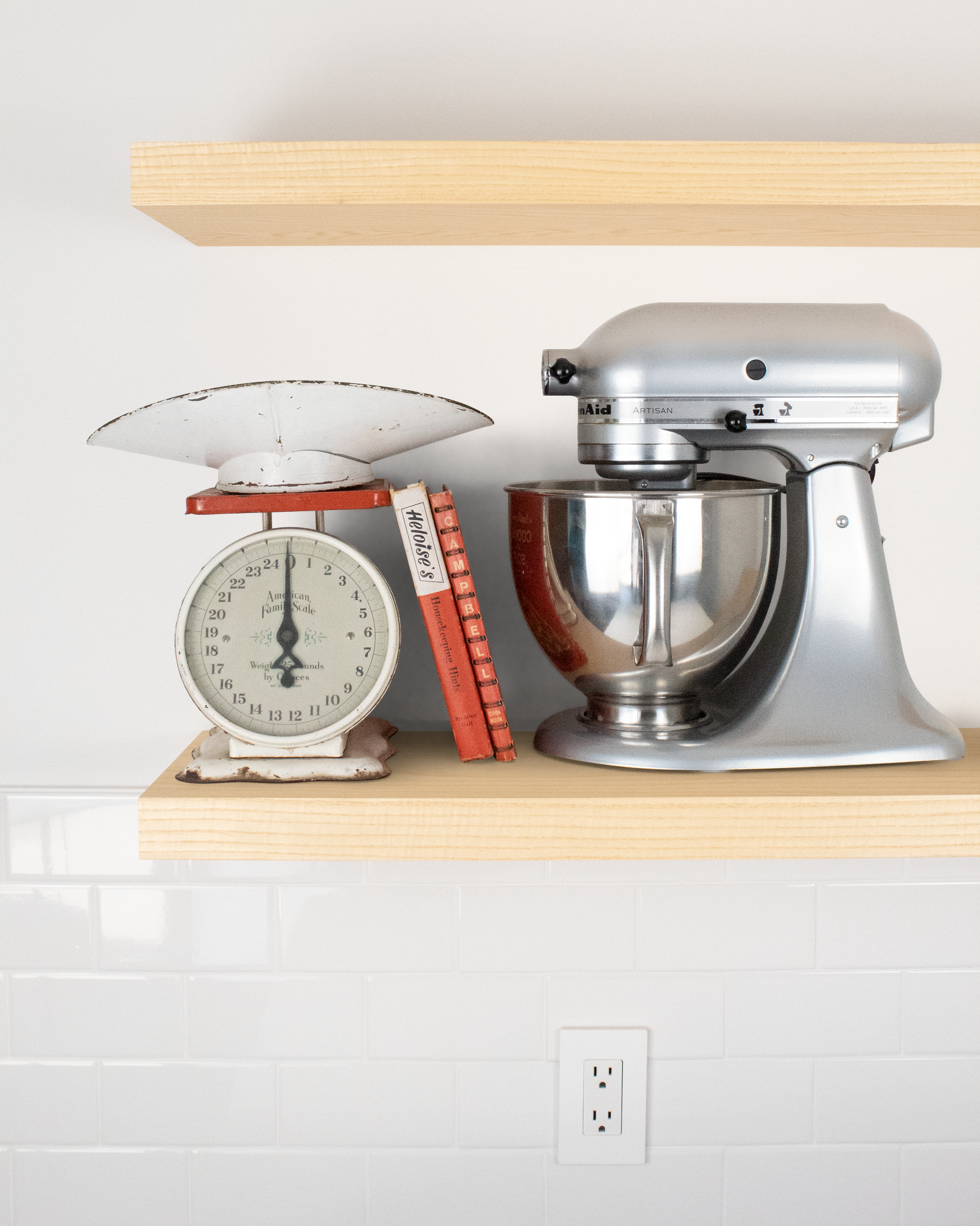 Two ash floating shelves on a wall with accessories on the bottom floating shelf