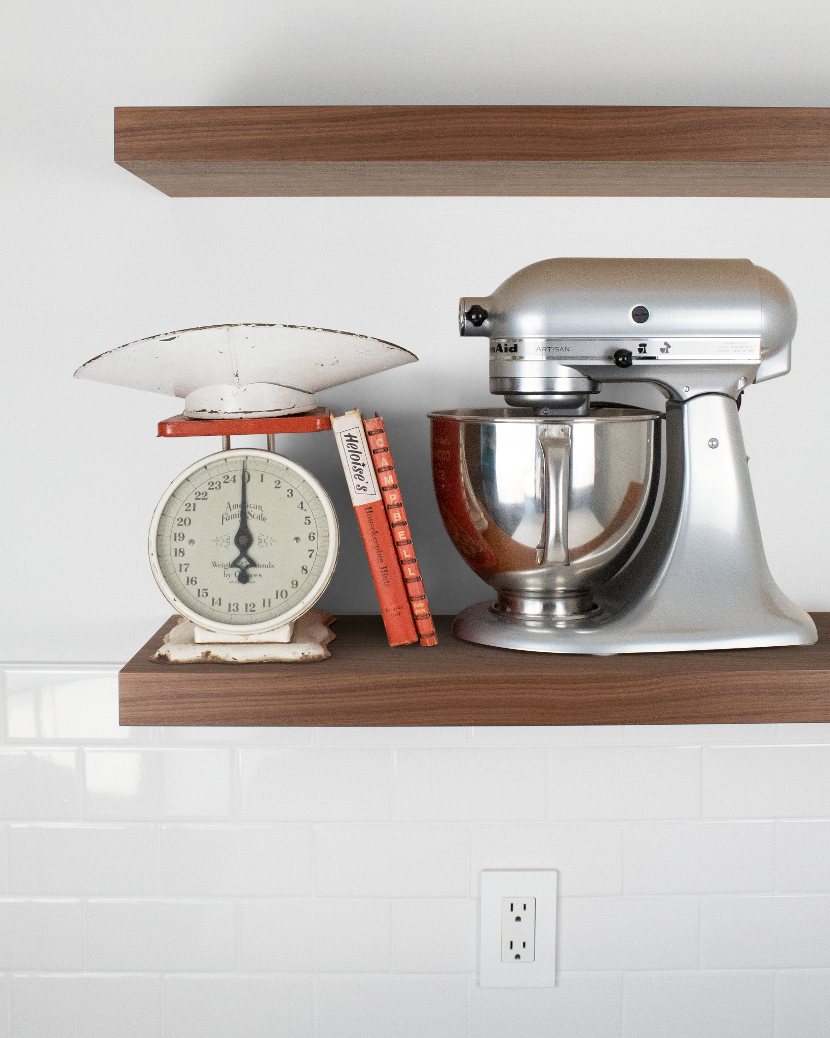 Front view of floating shelves in walnut with scale, books and mixer placed on bottom shelf