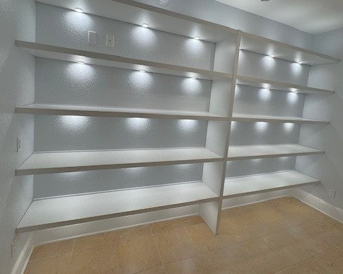 built-in white shelving illuminated by integrated puck lights.